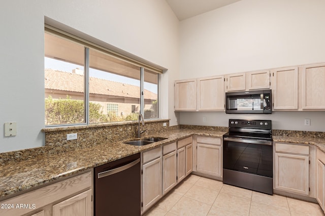 kitchen featuring light brown cabinetry, light tile patterned flooring, stone counters, black appliances, and sink