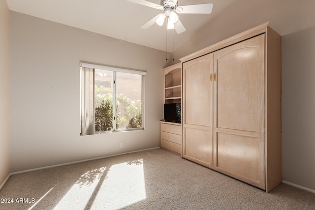 unfurnished bedroom with a closet, ceiling fan, vaulted ceiling, and light colored carpet