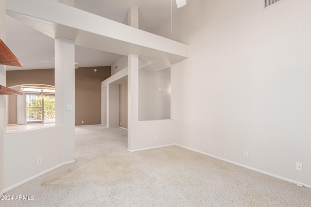 carpeted empty room featuring high vaulted ceiling