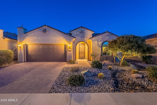 mediterranean / spanish home with decorative driveway, a garage, and stucco siding