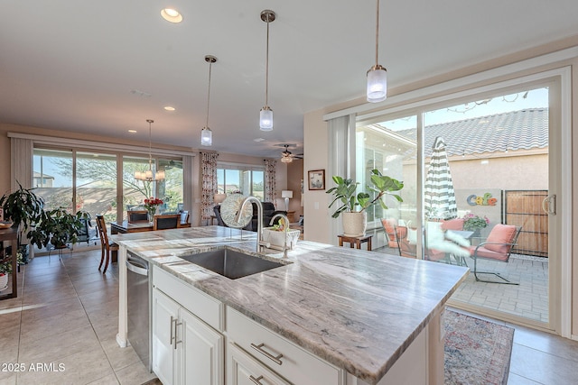 kitchen with a sink, light stone counters, a wealth of natural light, and light tile patterned floors