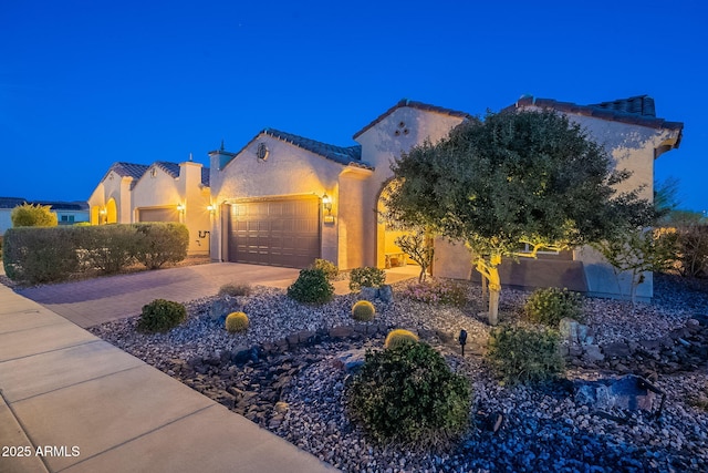 view of front of property with a tile roof, decorative driveway, an attached garage, and stucco siding