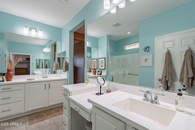 bathroom featuring two vanities, visible vents, a stall shower, and a sink