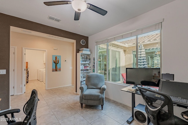 office area with washing machine and clothes dryer, visible vents, baseboards, light tile patterned floors, and a ceiling fan