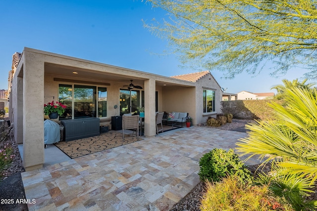 rear view of house featuring stucco siding, a ceiling fan, a tile roof, a patio, and an outdoor hangout area