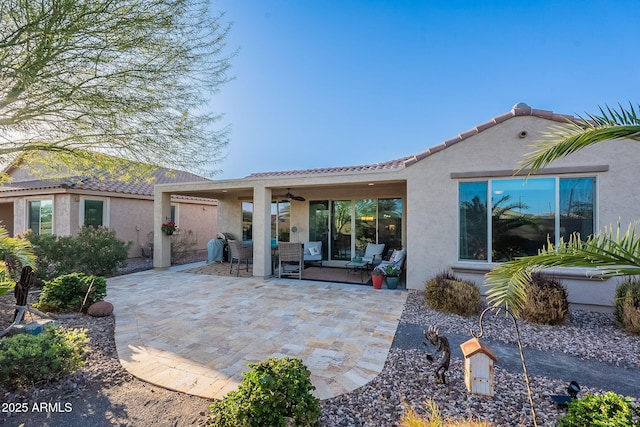 back of property featuring stucco siding, ceiling fan, and a tiled roof