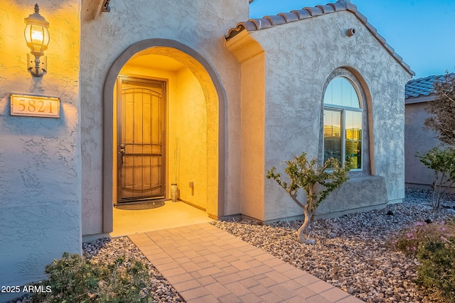 entrance to property featuring stucco siding and a tiled roof