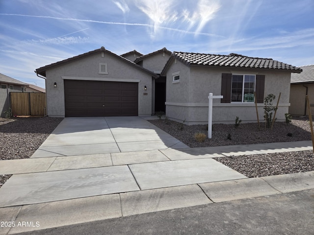 ranch-style home featuring stucco siding, a tiled roof, concrete driveway, and fence