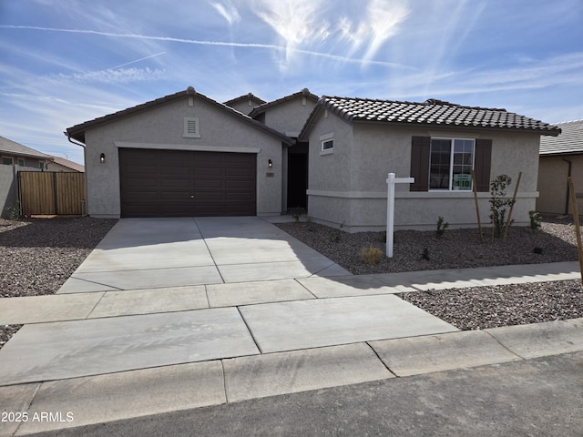 ranch-style home featuring a garage, concrete driveway, a tiled roof, fence, and stucco siding