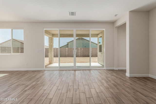 unfurnished room with visible vents, baseboards, and wood finished floors