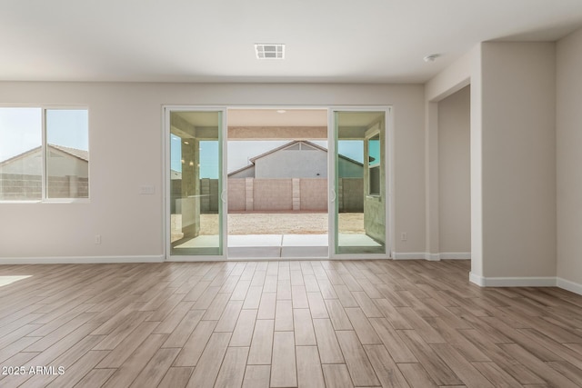 spare room featuring visible vents, baseboards, and wood finished floors