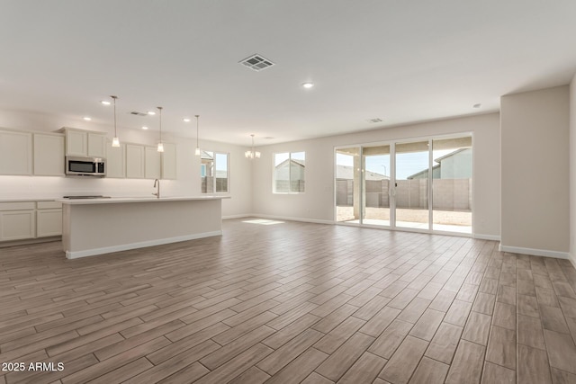 unfurnished living room featuring baseboards, visible vents, recessed lighting, a sink, and light wood-type flooring