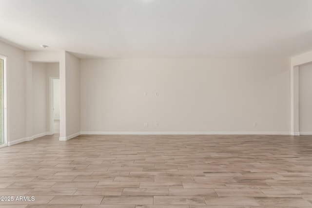 spare room featuring light wood finished floors and baseboards