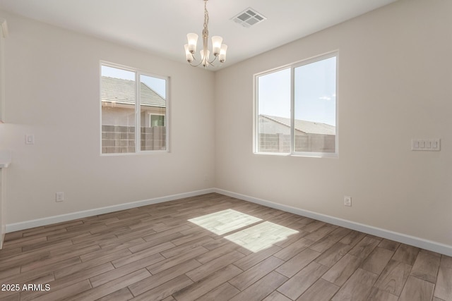 empty room with visible vents, light wood-style flooring, baseboards, and an inviting chandelier