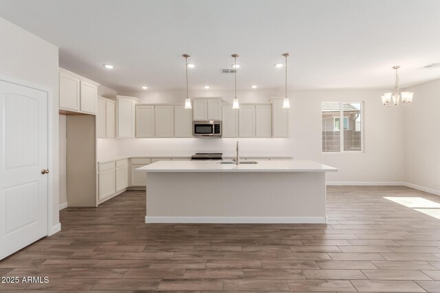 kitchen with visible vents, wood finish floors, a sink, appliances with stainless steel finishes, and a chandelier