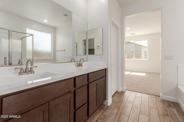 bathroom featuring double vanity, visible vents, a shower with shower door, and a sink