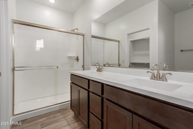 full bathroom featuring a sink, wood finished floors, a stall shower, and double vanity
