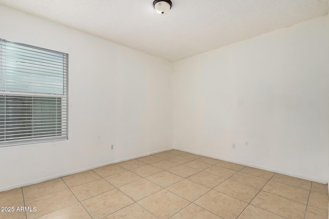 empty room featuring light tile patterned floors and a textured ceiling