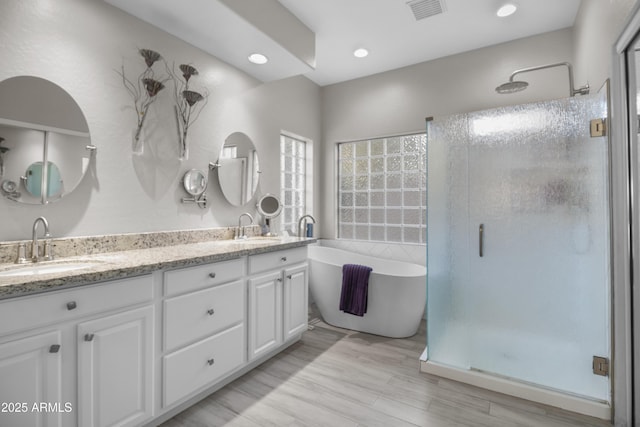 bathroom with plus walk in shower, hardwood / wood-style flooring, and vanity