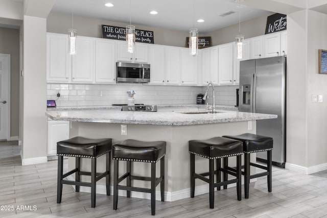 kitchen featuring sink, white cabinets, appliances with stainless steel finishes, and a kitchen island with sink