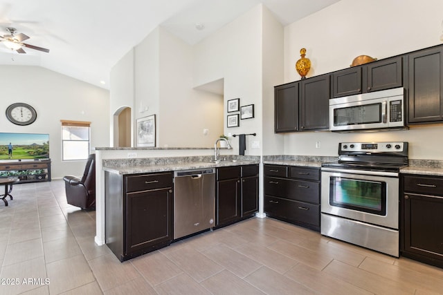 kitchen with dark brown cabinetry, appliances with stainless steel finishes, high vaulted ceiling, and sink