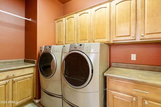 laundry room featuring washer and clothes dryer and cabinets