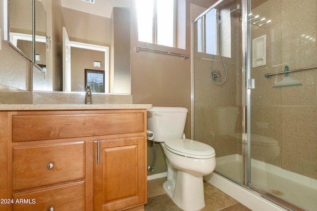 bathroom with tile patterned flooring, a shower with shower door, vanity, and toilet