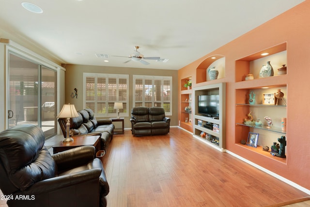 living room featuring light hardwood / wood-style floors, ceiling fan, and built in features