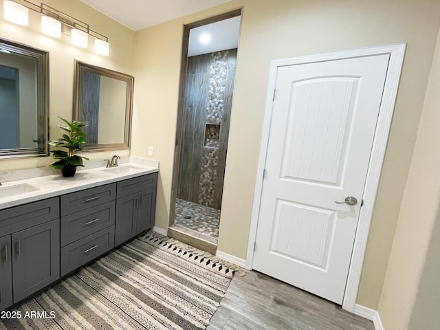 bathroom with a tile shower, vanity, and hardwood / wood-style floors