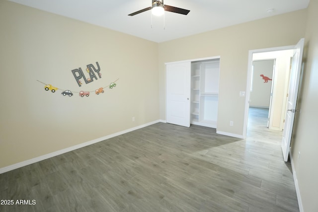 unfurnished bedroom featuring hardwood / wood-style floors, a closet, and ceiling fan