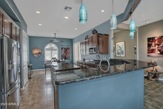 kitchen with pendant lighting, stainless steel appliances, dark tile patterned floors, and dark brown cabinetry