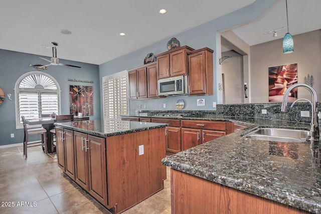 kitchen with light tile patterned floors, sink, ceiling fan, hanging light fixtures, and a center island