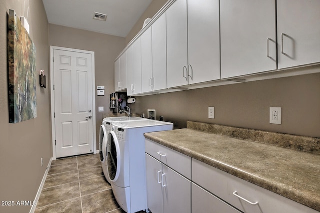 clothes washing area with cabinets, washing machine and clothes dryer, and tile patterned floors