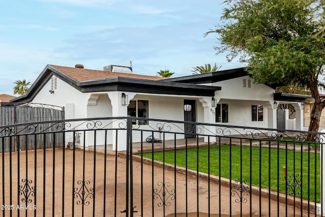 view of front of home with a fenced front yard, a front lawn, a shingled roof, and stucco siding