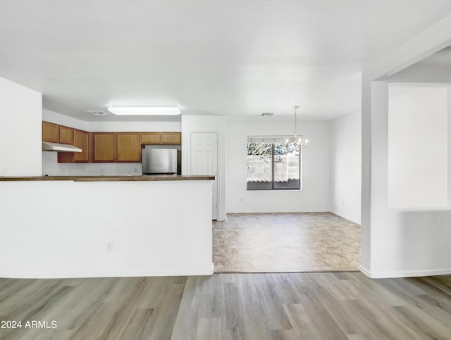 kitchen featuring stainless steel fridge, an inviting chandelier, pendant lighting, and light hardwood / wood-style floors