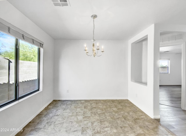 unfurnished room with plenty of natural light and an inviting chandelier