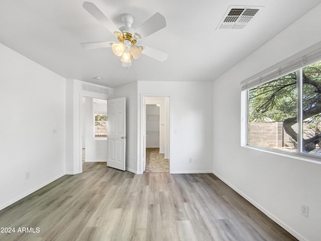 unfurnished bedroom with a closet, light hardwood / wood-style floors, a spacious closet, and ceiling fan