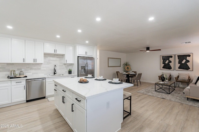 kitchen with appliances with stainless steel finishes, white cabinetry, a kitchen island, and sink