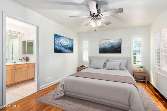 bedroom with multiple windows, ensuite bath, light wood-type flooring, and ceiling fan