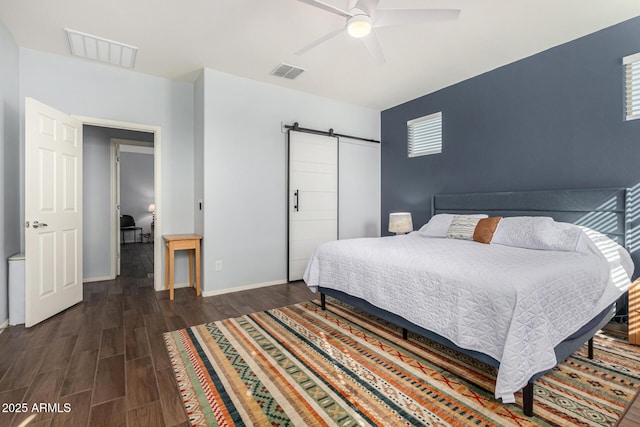 bedroom with dark wood-type flooring, a barn door, and ceiling fan