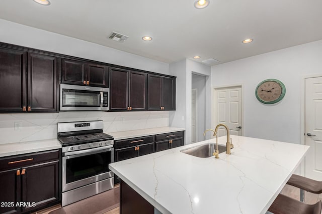 kitchen with stainless steel appliances, an island with sink, and sink