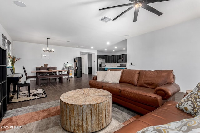 living room with dark hardwood / wood-style flooring and ceiling fan with notable chandelier