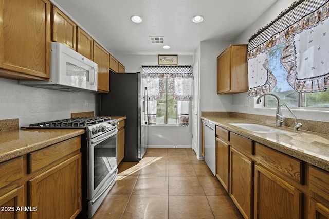 kitchen featuring light stone countertops, sink, appliances with stainless steel finishes, and light tile patterned flooring