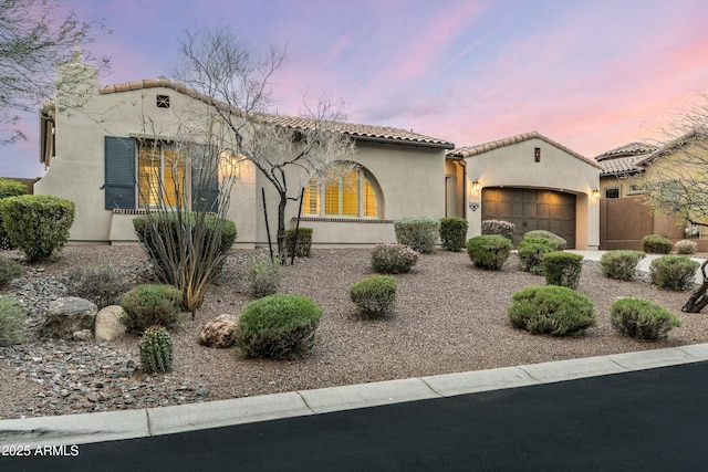 mediterranean / spanish house with stucco siding, a tile roof, and a garage