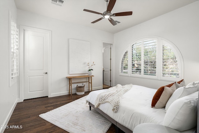 bedroom with ceiling fan, visible vents, baseboards, and wood finished floors