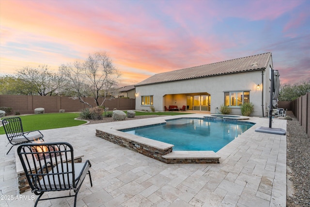 view of pool featuring a lawn, a pool with connected hot tub, a fenced backyard, and a patio area