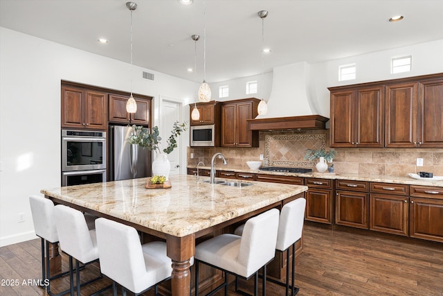 kitchen with visible vents, backsplash, appliances with stainless steel finishes, custom exhaust hood, and a sink