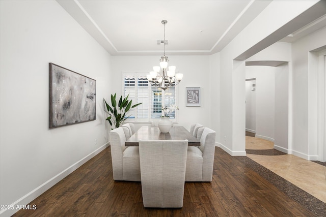 dining area featuring visible vents, baseboards, dark wood finished floors, a tray ceiling, and a chandelier