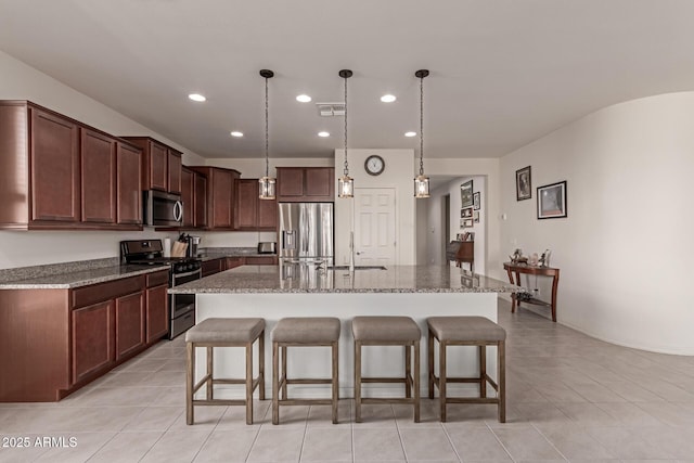 kitchen featuring light stone countertops, a breakfast bar, stainless steel appliances, sink, and a center island with sink