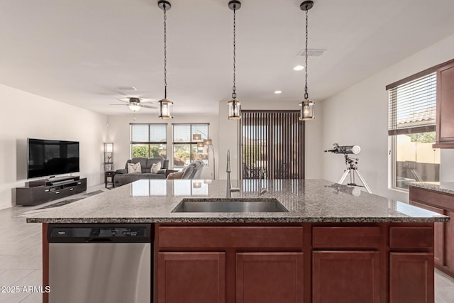 kitchen with stainless steel dishwasher, ceiling fan, sink, decorative light fixtures, and a center island with sink